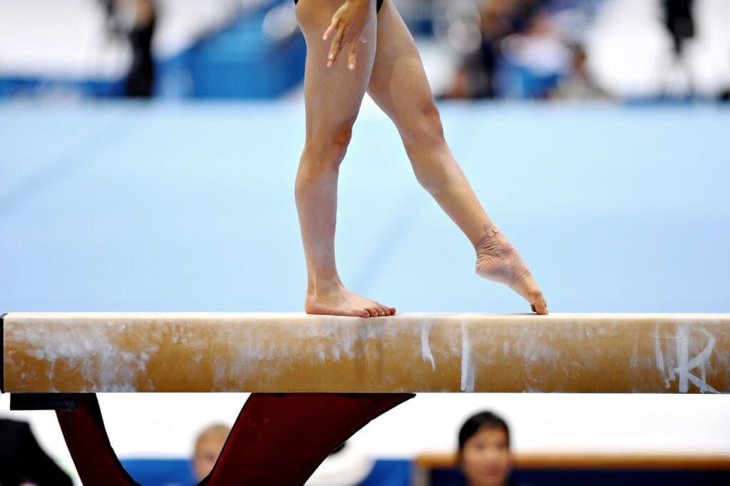 Legs of a gymnast are seen during an exercise on the balance beam apparatus